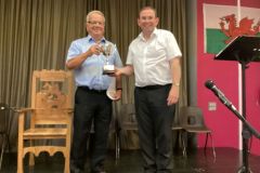 Geraint-James-cadeirydd-y-pwyllgor-yn-cyflwyno-Cwpan-Her-canu-emyn-dros-60-i-Gwyn-Jones